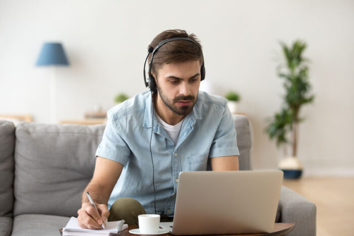 Serious man looking at laptop wearing headset learning foreign language